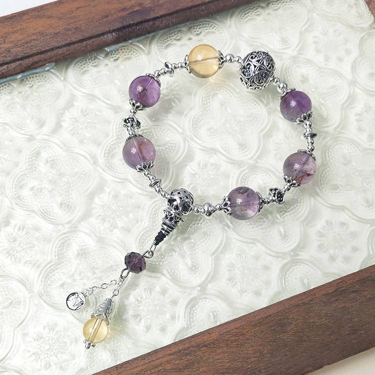 Healing multi-gemstone bracelet featuring amethyst and citrine charms for emotional well-being and energy balance.
