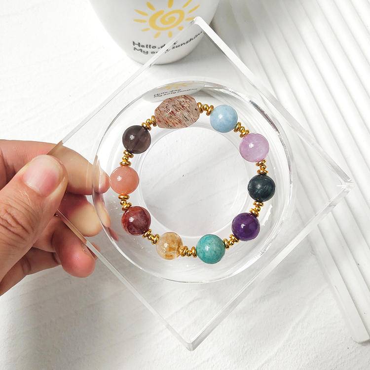 Healing multi-gemstone bracelet in black gold with amethyst, sunstone, aquamarine, citrine, lepidolite, smoky quartz, and red jade flower, promoting balance and positive energy.
