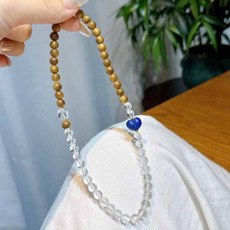 Clear quartz, agarwood, and lapis lazuli multi-wrap bracelet promoting healing, balance, and positive energy.
