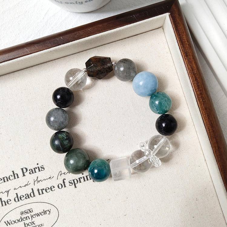 Dark green multi-gemstone bracelet with green dragon quartz, green rutilated quartz, aquamarine, gray rabbit hair quartz, blue crystal stone, clear quartz, and black rutilated quartz, promoting healing, balance, and positive energy.
