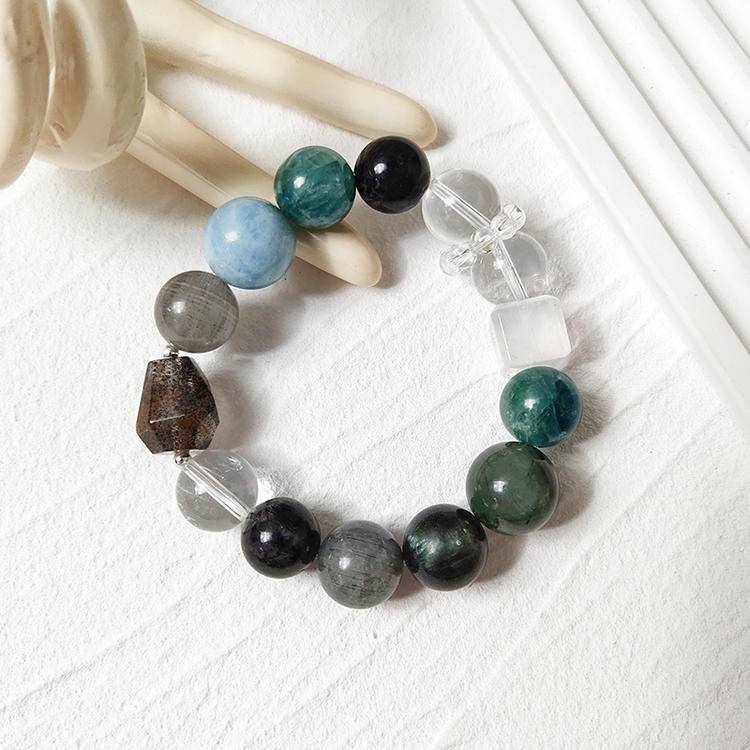 Multi-gemstone bracelet with dark green crystals including green dragon quartz, green rutilated quartz, aquamarine, gray rabbit hair quartz, blue crystal stone, clear quartz, and black rutilated quartz, designed to enhance healing, balance, and positive energy.
