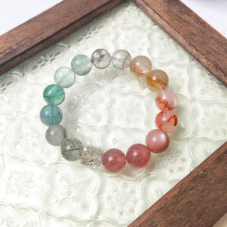 Healing multi-gemstone bracelet featuring strawberry quartz, green gems, red and yellow jade flowers, fluorite, green phantom quartz, sunstone, and black gold crystal for balance and well-being.

